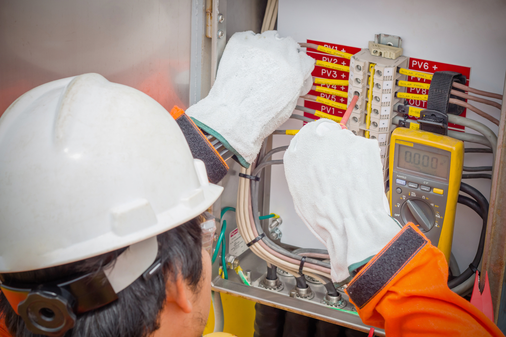 Figura 12: Electricista usando el multímetro digital para comprobar la resistencia y voltaje de los cuadros eléctricos.